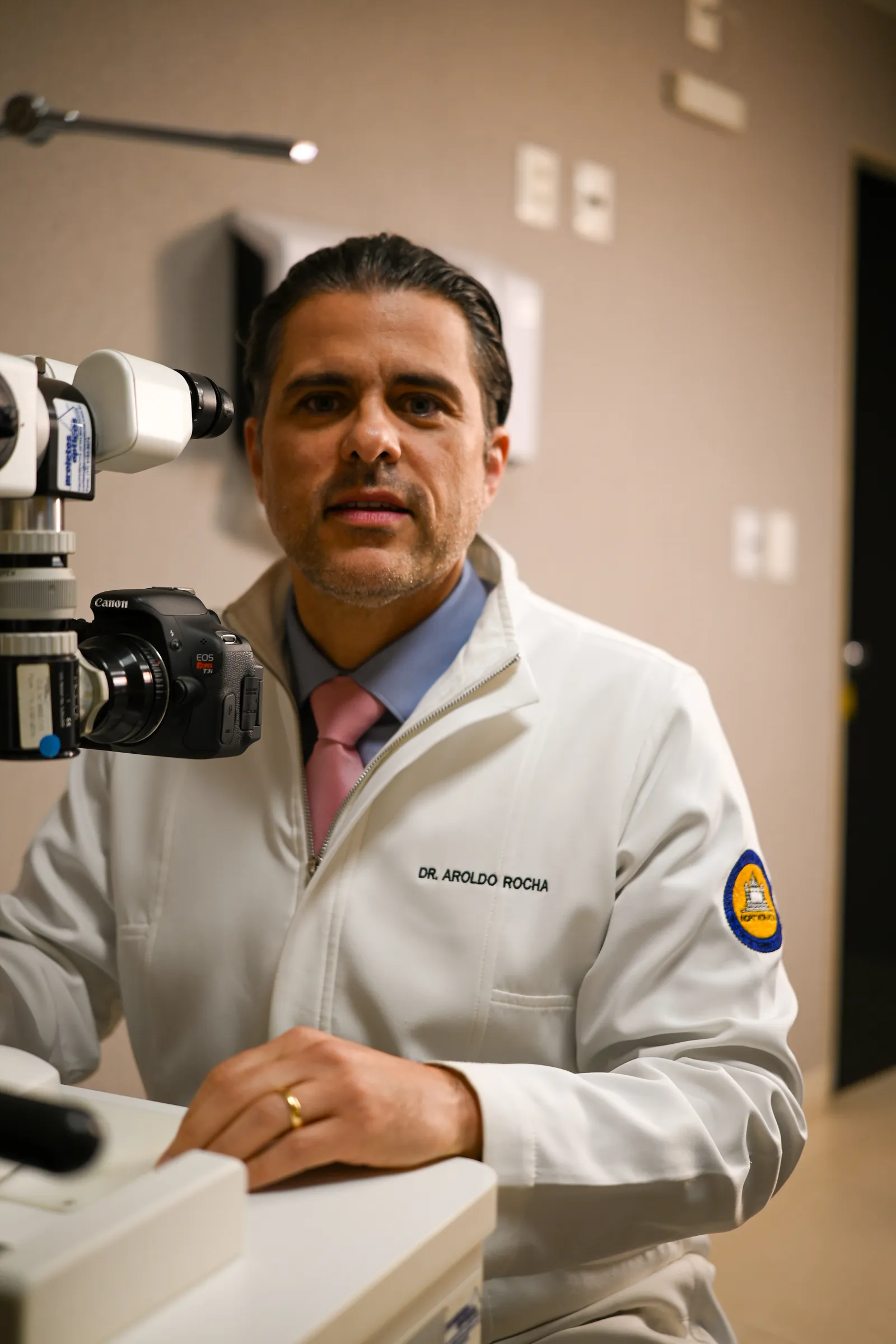 Dr. Aroldo Rocha, oftalmologista, em consultório com equipamento de avaliação da visão